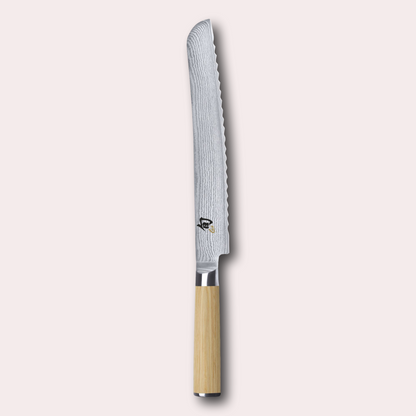 Kai Shun White 23cm bread knife.  Light ash coloured pakkawood handle, meets a VG Max steel core blade wrapped in 32 layers of Damascus Steel.